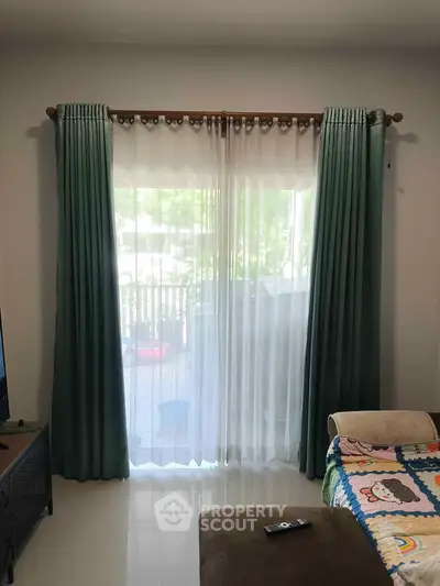 Cozy living room with elegant curtains and plush seating, offering a serene view of the outdoors.