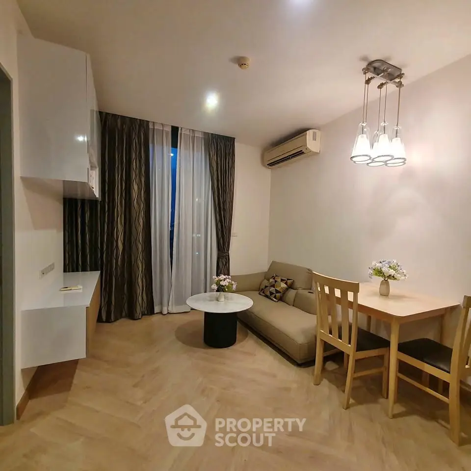 Cozy living room with modern decor and dining area, featuring elegant lighting and air conditioning.