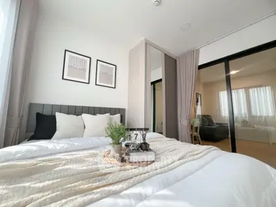 Modern bedroom with cozy decor and natural light, featuring a stylish bed and elegant furnishings.