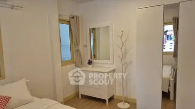 Cozy bedroom with white furniture and natural light, perfect for relaxation.