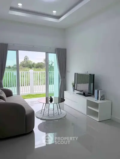 Modern living room with sleek furniture and large glass doors opening to a scenic view.