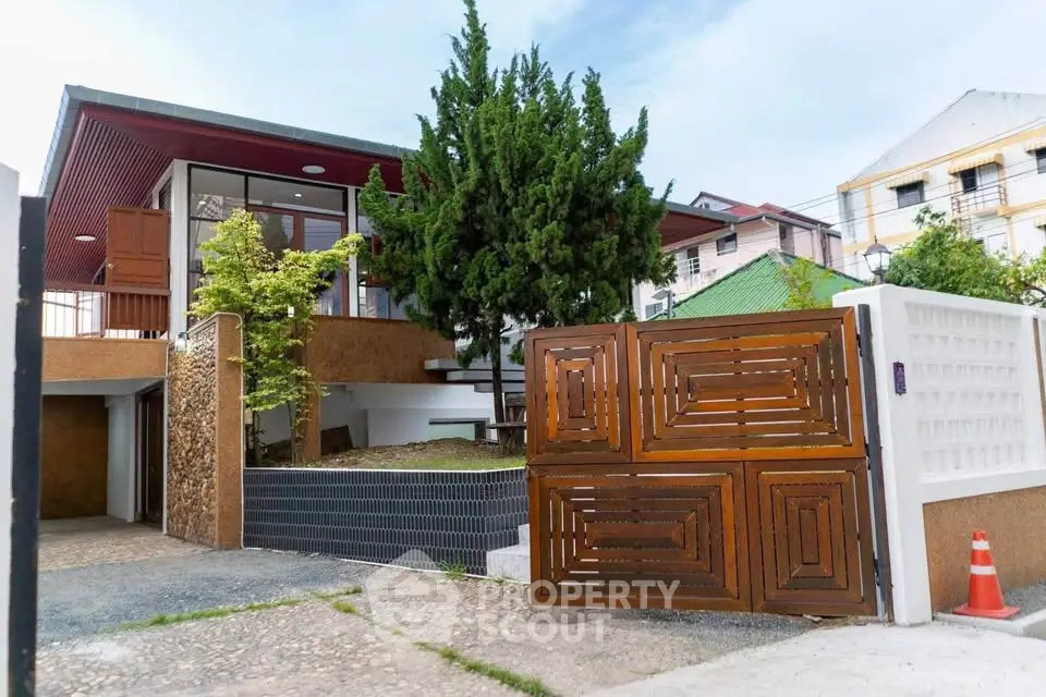 Modern architectural home with unique wooden gate and lush greenery
