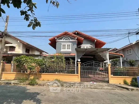 Charming two-story house with gated entrance and lush garden in a serene neighborhood.
