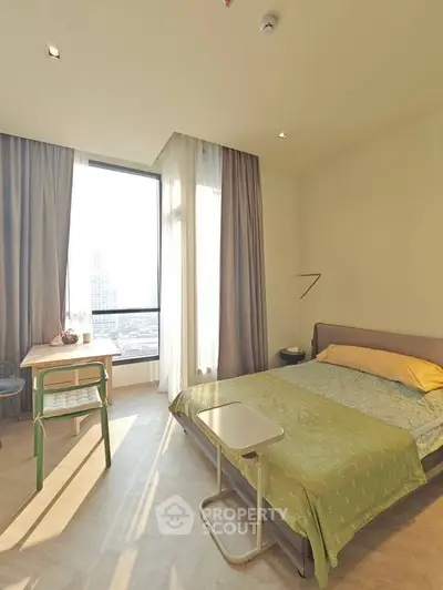 Bright and cozy bedroom with large window and city view, perfect for relaxation.