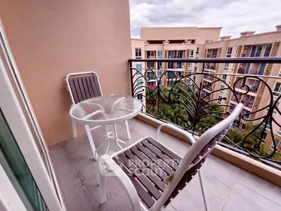 Charming balcony with stylish furniture and scenic view of modern apartment complex.
