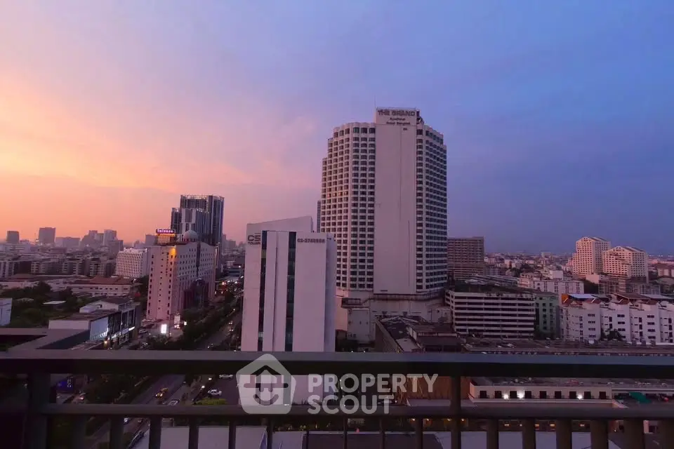 Stunning cityscape view from a high-rise balcony at sunset, showcasing urban skyline and vibrant sky.