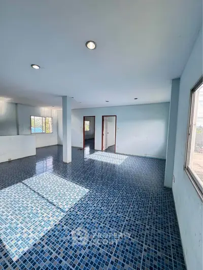 Spacious interior with blue tiled flooring and ample natural light, perfect for versatile living space.