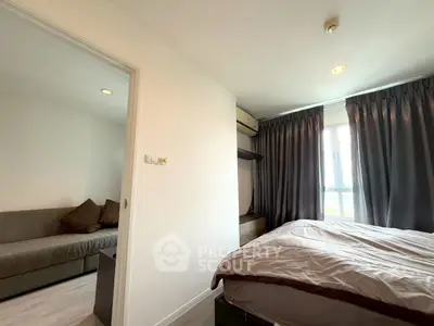 Cozy bedroom with modern decor and natural light, adjacent to a stylish living area.
