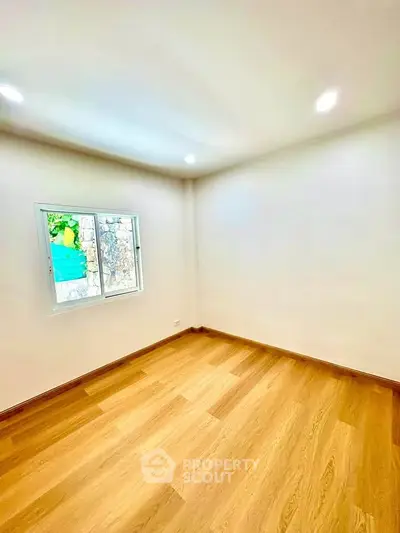 Spacious empty room with wooden flooring and bright window view