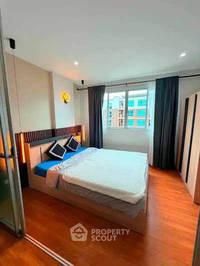 Modern bedroom with stylish decor and large window offering natural light.