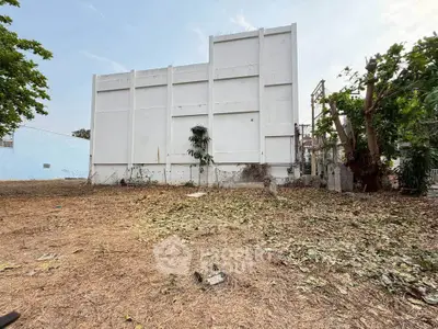 Spacious plot with potential for development, featuring a large white building and open land.