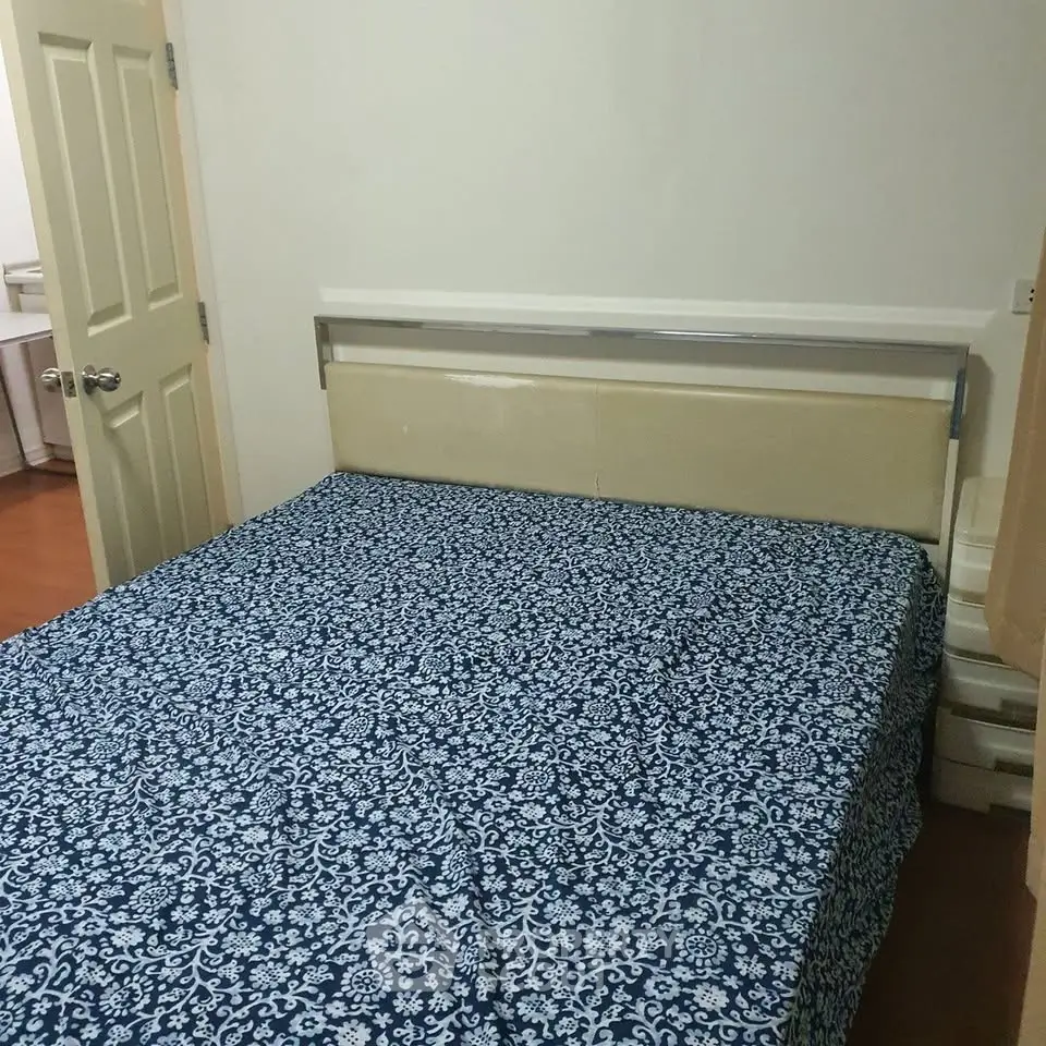 Cozy bedroom with patterned bedspread and wooden flooring, ideal for restful nights.