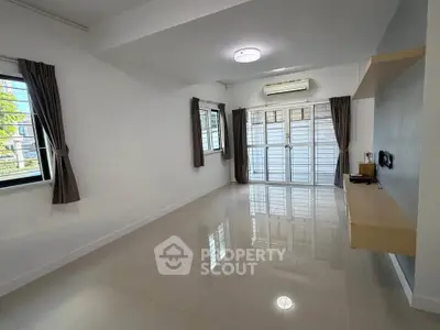 Spacious living room with large windows and modern air conditioning unit.