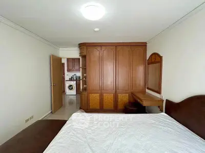 Spacious bedroom with built-in wardrobe and adjacent kitchen view