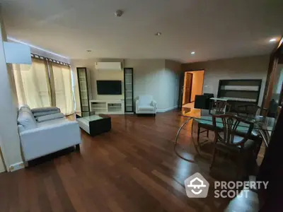 Spacious living room with wooden flooring and modern furniture in a cozy apartment.