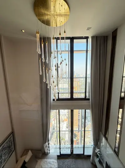 Luxurious high-ceiling living room with stunning city view and elegant chandelier