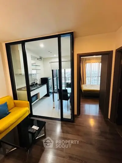 Modern apartment with open kitchen and cozy living area featuring a vibrant yellow sofa.