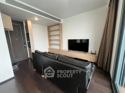 Modern living room with sleek black leather sofa and flat-screen TV, featuring elegant wooden shelving.