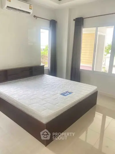 Spacious bedroom with large windows and modern air conditioning unit.