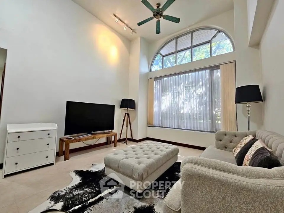 Spacious living room with high ceiling, large window, and modern decor