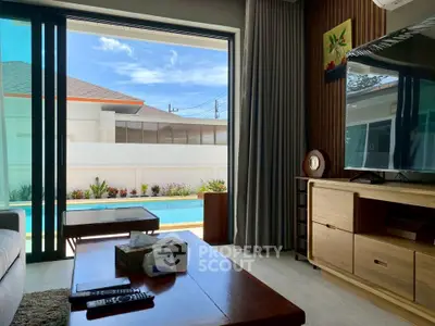 Luxurious living room with pool view, modern furniture, and large sliding glass doors.