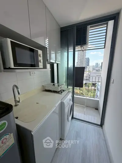 Modern kitchen with washing machine and city view from balcony.