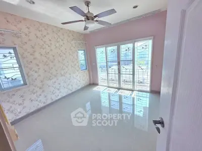 Bright empty room with floral wallpaper and large windows, perfect for customization.