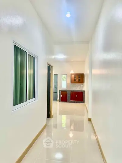 Bright hallway leading to a modern kitchen with sleek cabinetry and glossy floors.