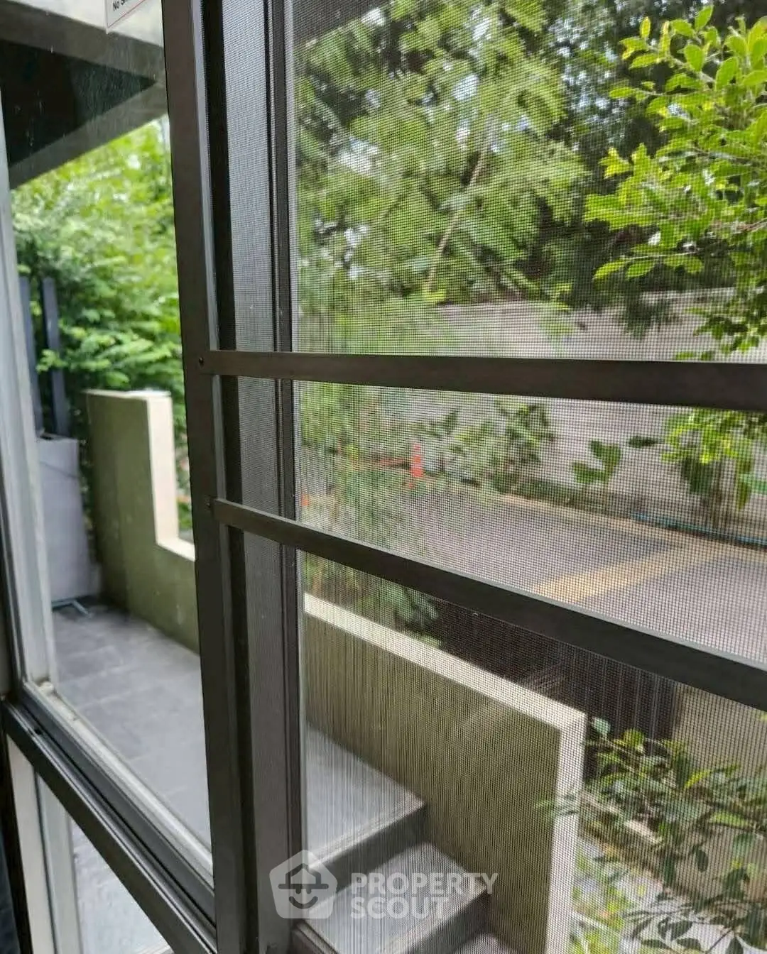 Charming garden view from a modern window, showcasing lush greenery and serene outdoor space.