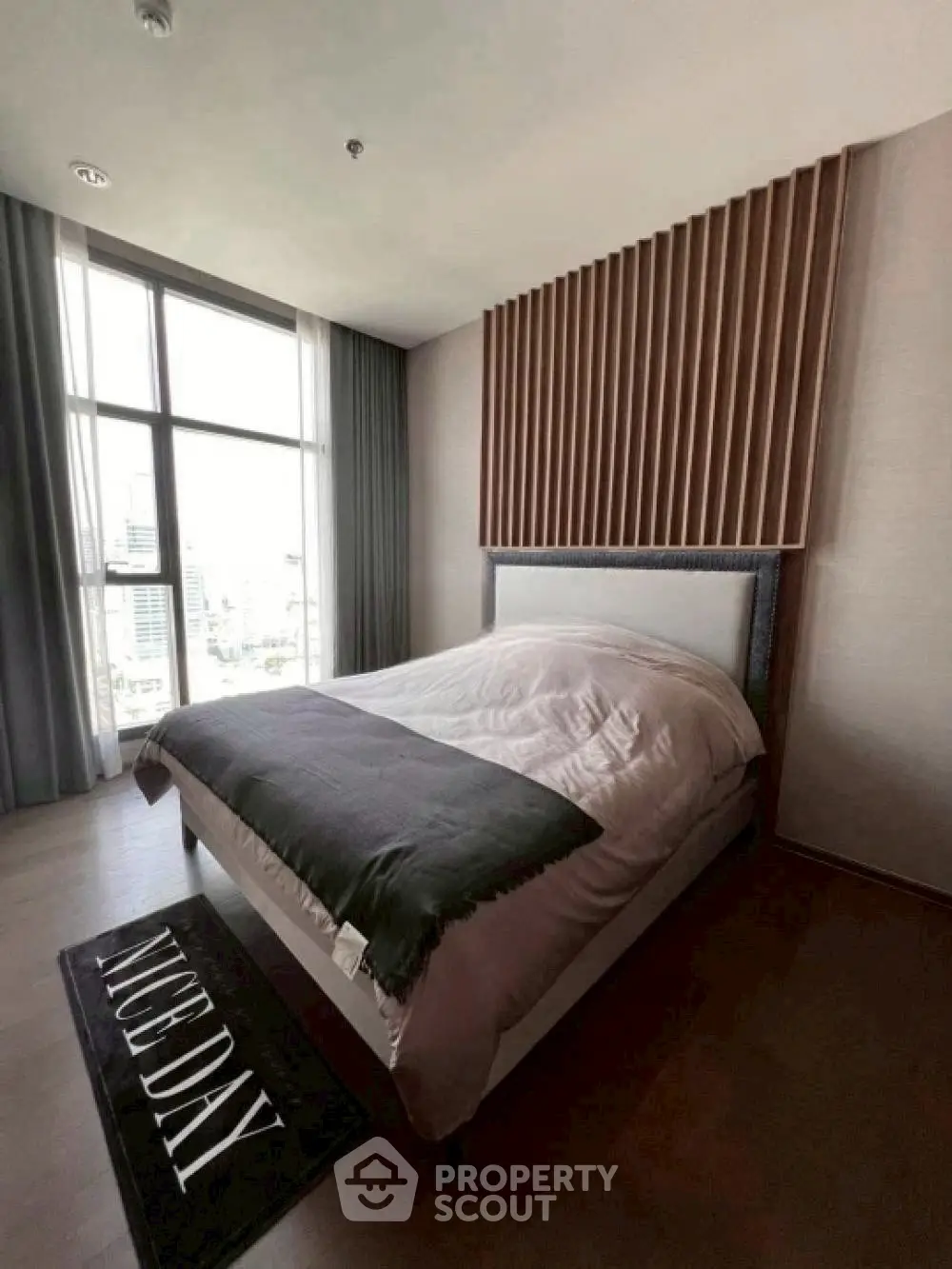 Modern bedroom with large window and stylish wood paneling, offering a cozy and inviting atmosphere.