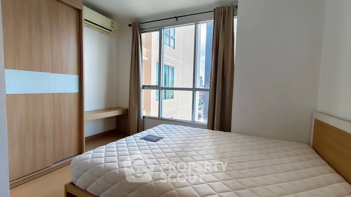 Modern bedroom with large window and built-in wardrobe in urban apartment