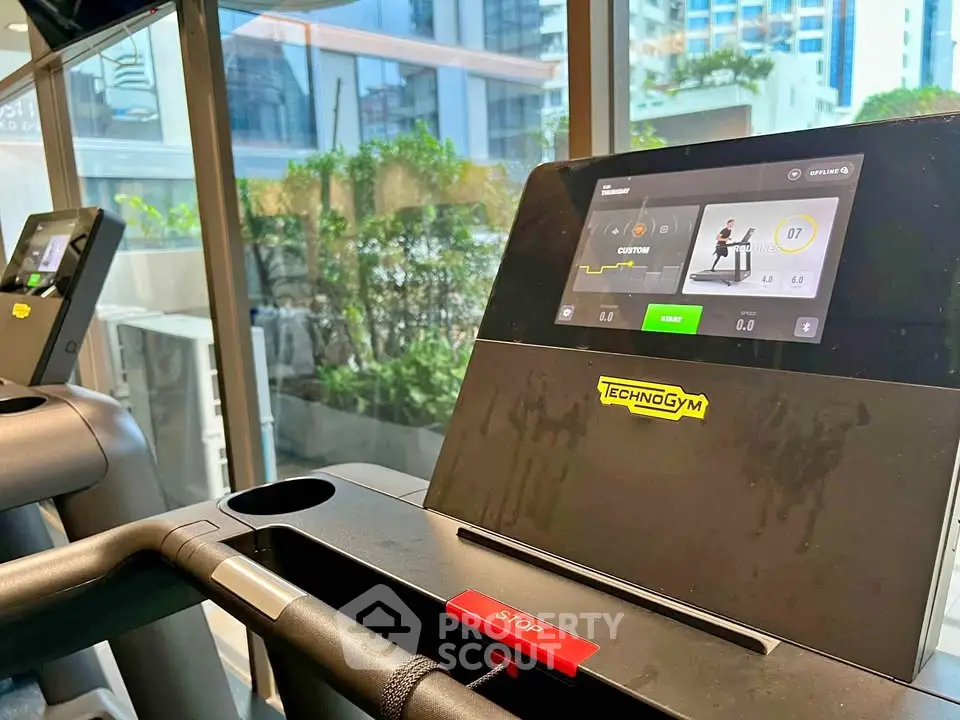 Modern gym with state-of-the-art Technogym treadmills and city view, perfect for fitness enthusiasts.
