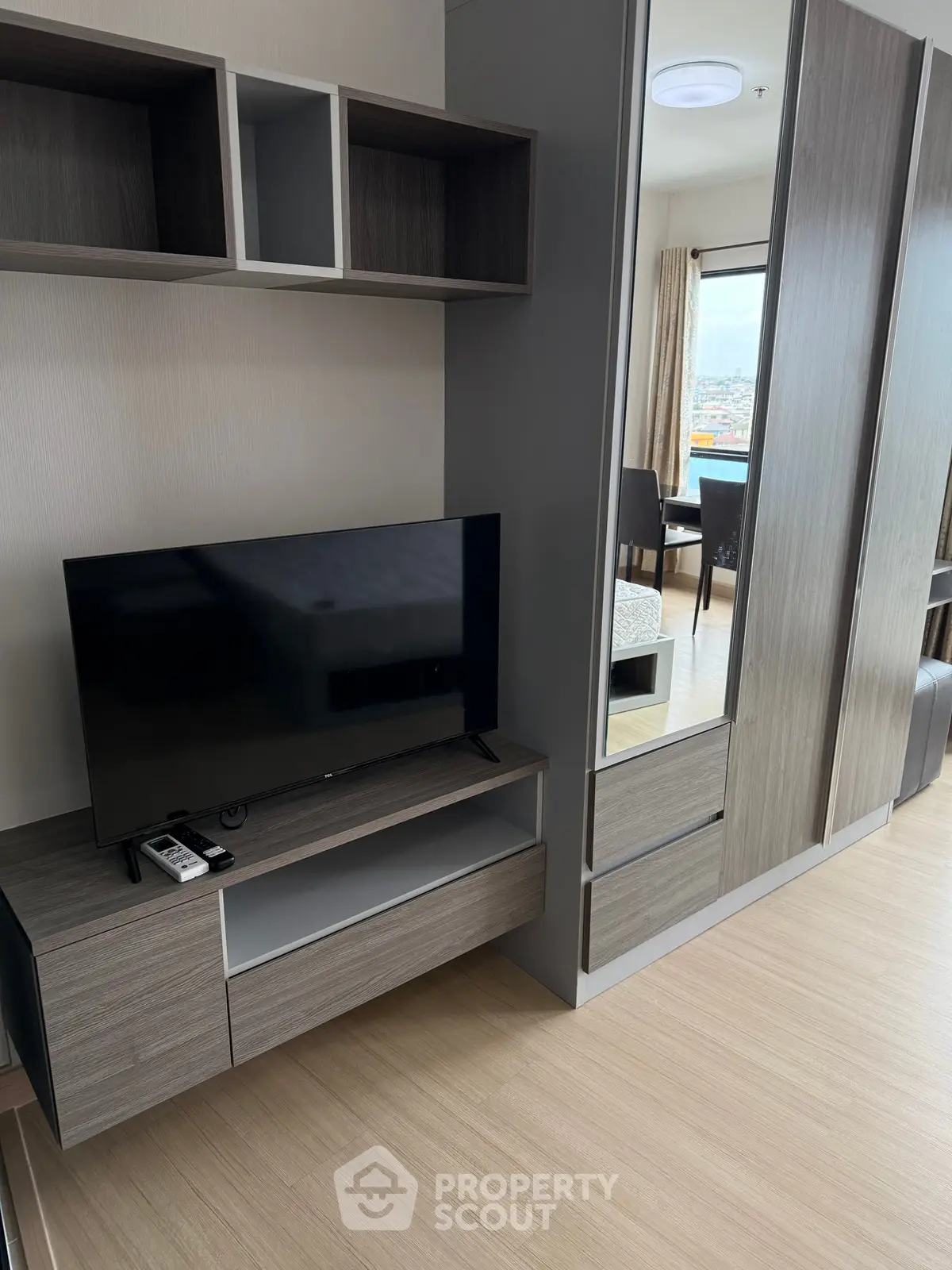 Modern living room with sleek TV unit and mirrored wardrobe in stylish apartment.