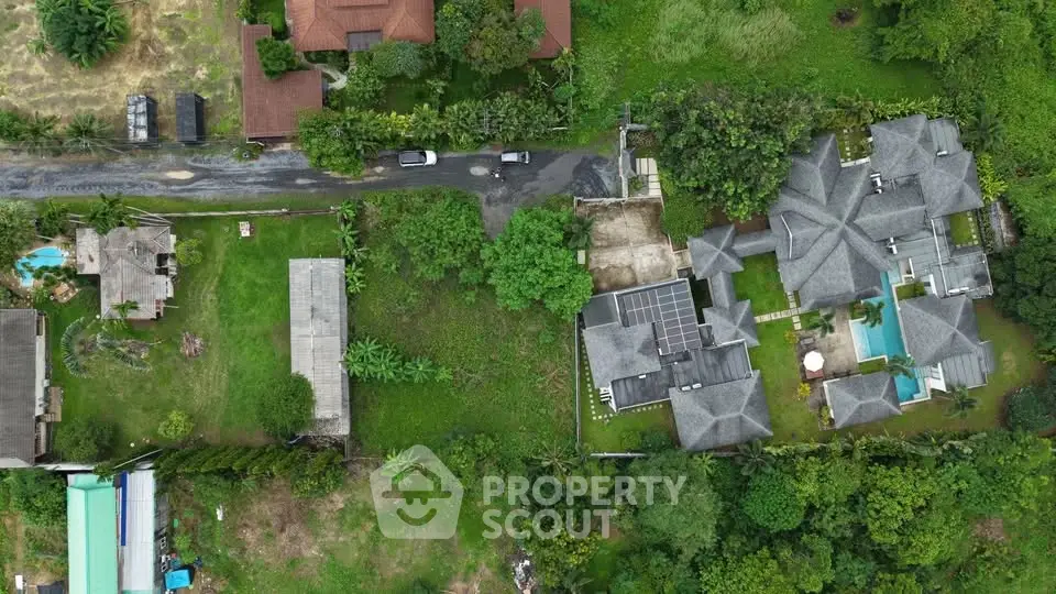 Aerial view of luxurious estate with lush greenery and spacious layout, featuring a pool and expansive garden.