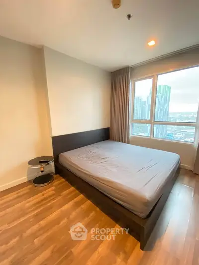 Modern bedroom with city view, featuring sleek wooden flooring and large windows for natural light.