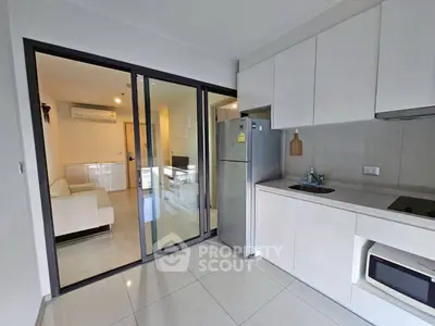 Modern kitchen with sleek cabinetry and open layout leading to a cozy living room.
