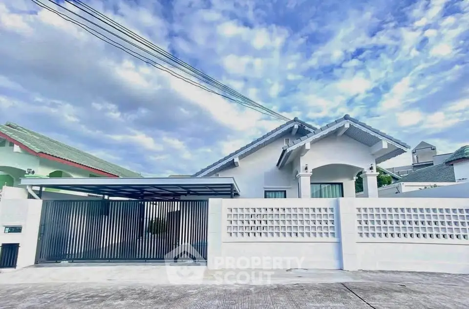Charming single-story home with modern facade and gated driveway under a clear blue sky.