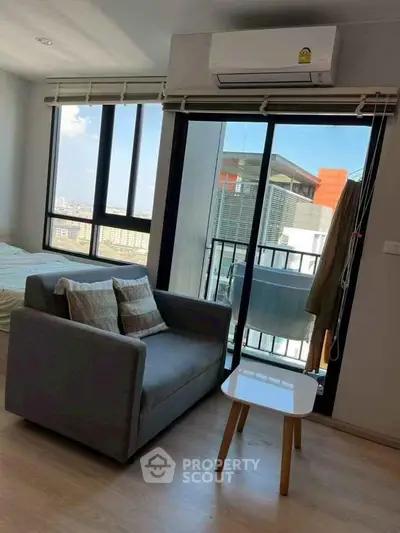 Modern living room with balcony view and air conditioning in urban apartment.