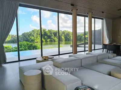 Luxurious living room with panoramic glass windows offering stunning lake views and modern minimalist decor.