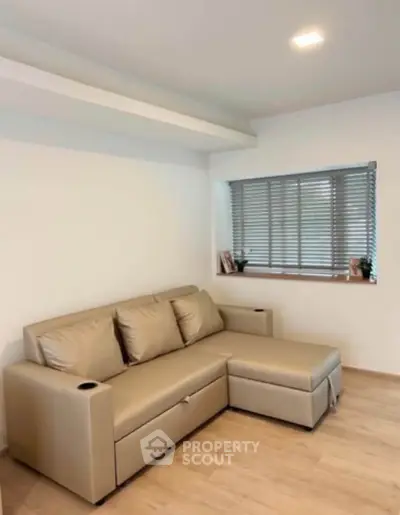 Modern living room with beige sectional sofa and wooden flooring