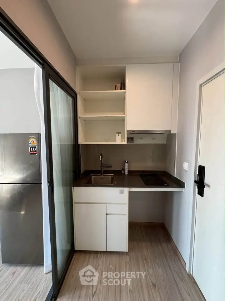 Modern compact kitchen with sleek cabinetry and built-in appliances in a stylish apartment.