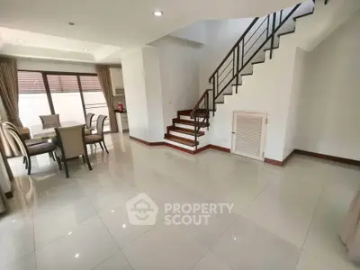 Spacious open-plan living and dining area with modern staircase and natural light.