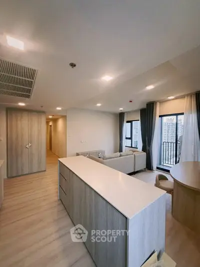 Spacious modern living room with large windows and stylish furniture in a high-rise apartment.