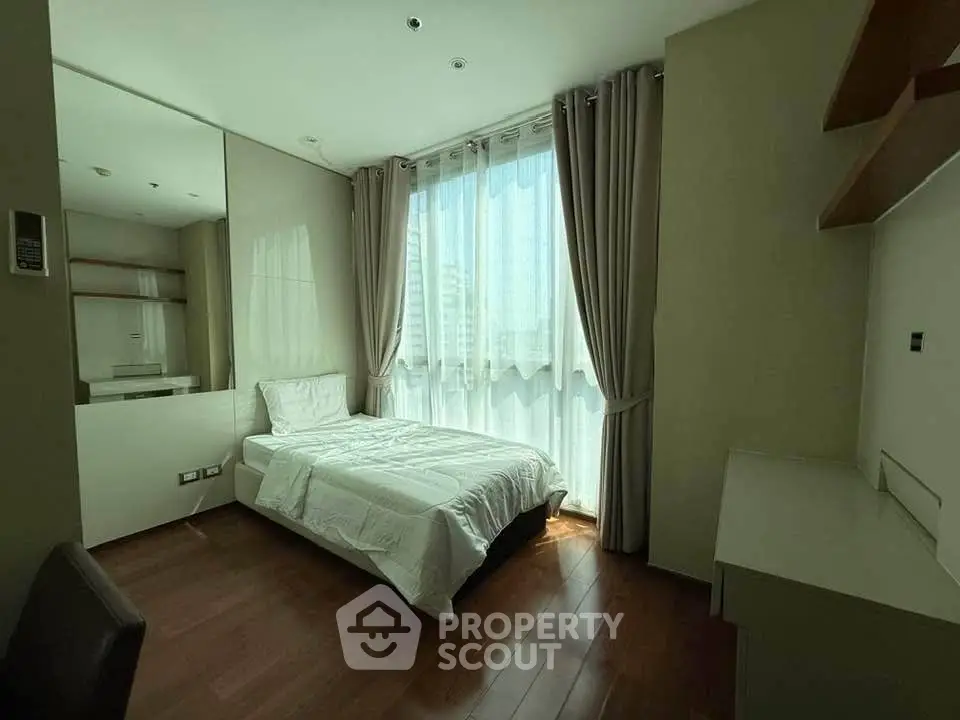 Cozy bedroom with large window and modern furnishings in a stylish apartment.