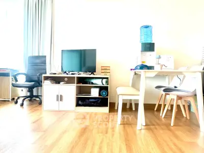 Modern living room with sleek furniture and wooden flooring, featuring a TV and office chair.