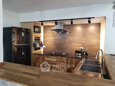 Modern kitchen with sleek appliances and wooden countertops in open layout design.