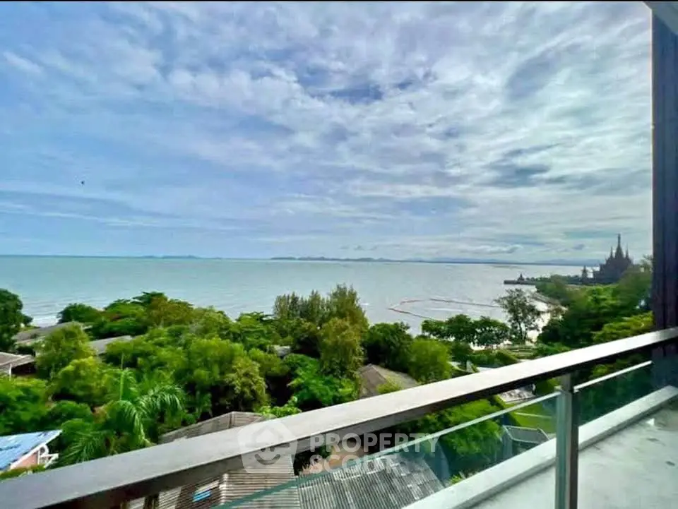 Stunning ocean view from a high-rise balcony overlooking lush greenery and distant coastline.