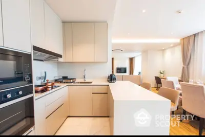 Modern kitchen with open layout flows seamlessly into a spacious living area, featuring built-in appliances and sleek cabinetry, perfect for entertaining.