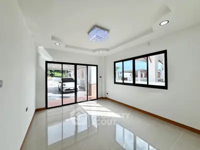 Spacious modern living room with large windows and sleek lighting, offering a bright and airy atmosphere.