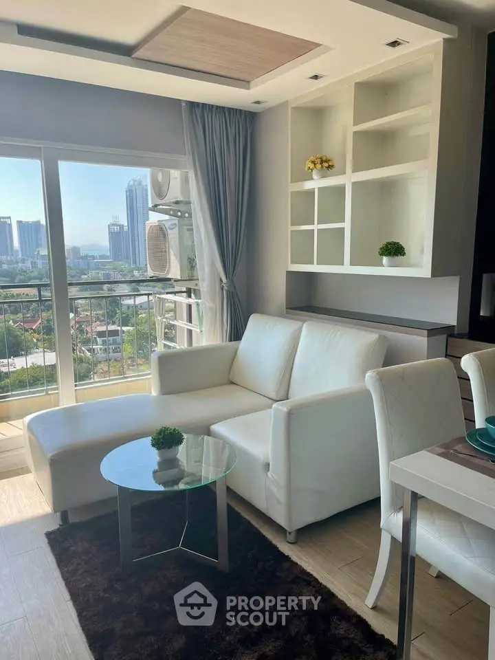 Modern living room with white sofa, glass table, and city view from balcony.